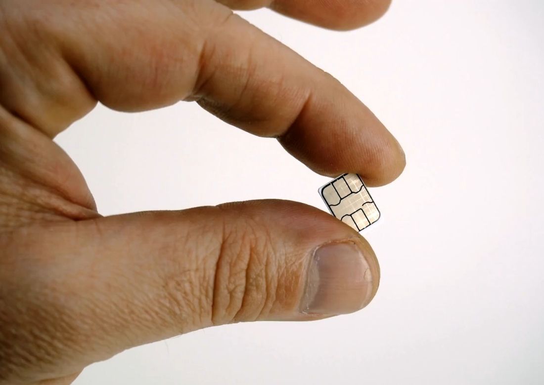 čovek drži karticu za telefon između dva prsta